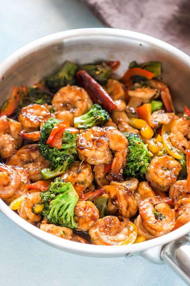 Teriyaki shrimp broccoli stir fry in a white pan with broccoli florets, peppers and glossy brown sauce
