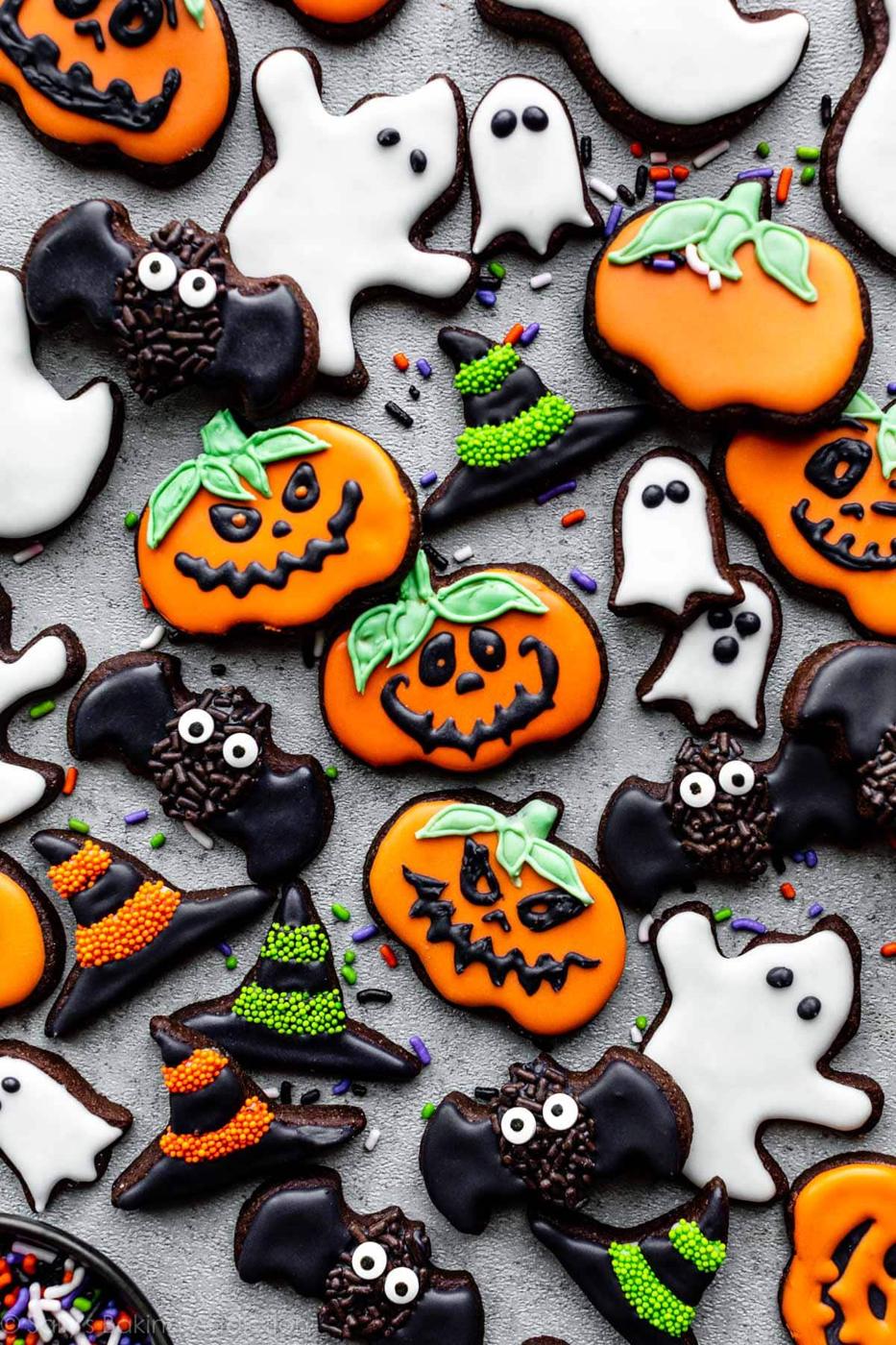 Chocolate Halloween sugar cookies with royal icing shaped as pumpkins, ghosts, bats and witch hats on a tray