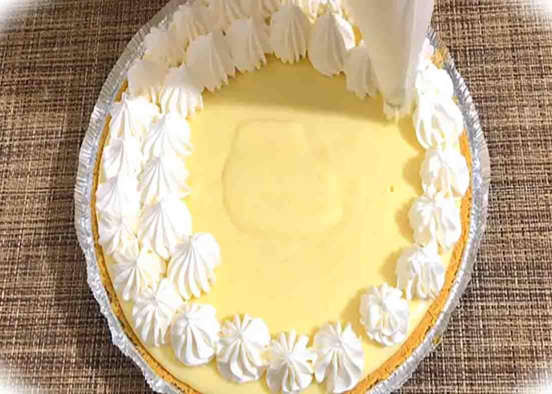 Decorating the creamy lemon icebox pie with whipped cream on top