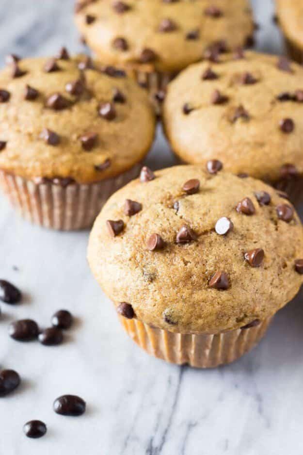 Cappuccino chocolate chip muffins with chips scattered over the domed tops, coffee beans on white marble