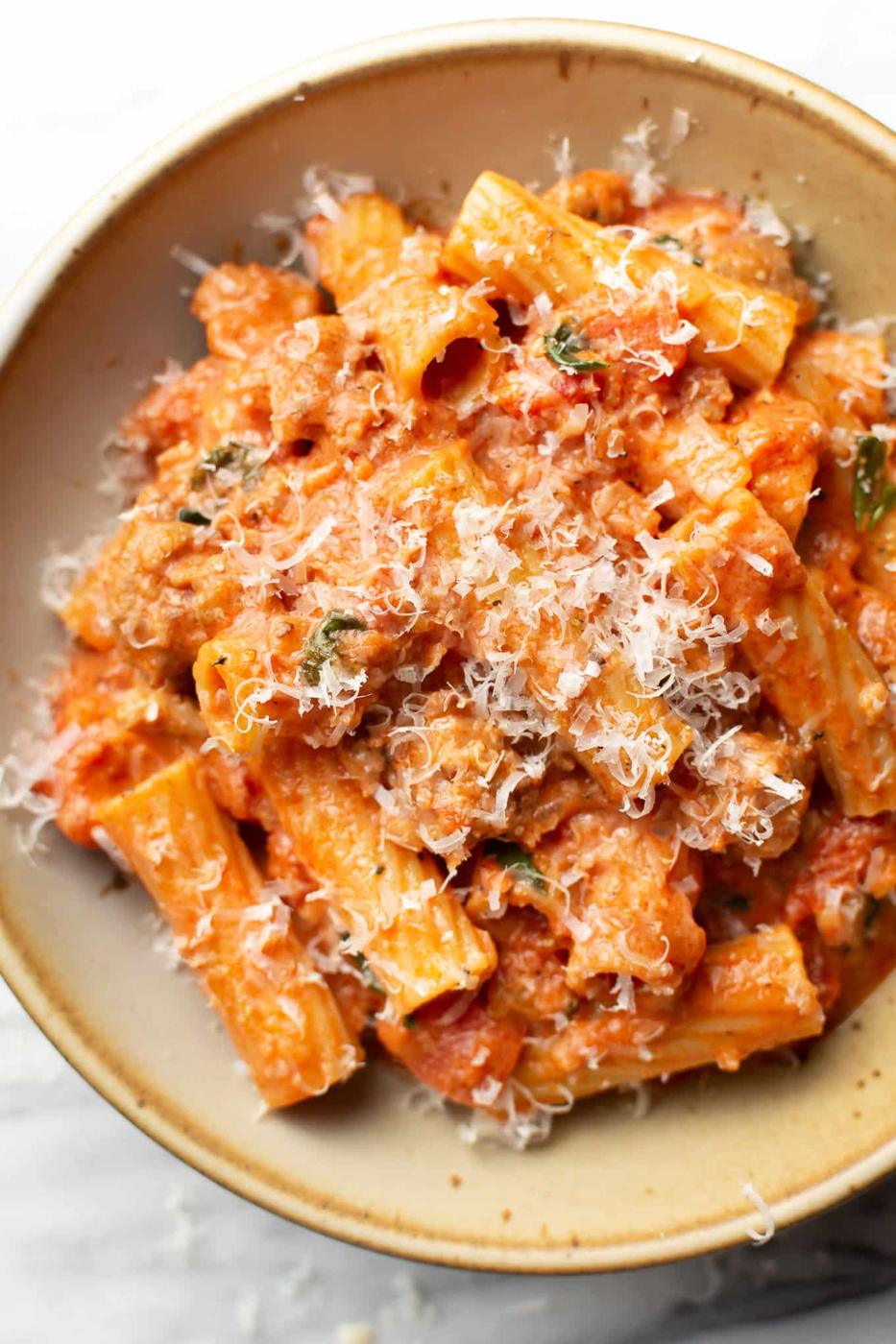 Spicy sausage rigatoni in a shallow bowl, rigatoni coated in creamy tomato sauce with grated parmesan on top