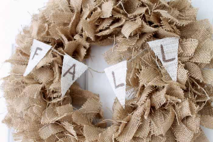 Fall burlap wreath of ruffled brown burlap strips with a small white FALL banner tied across the center
