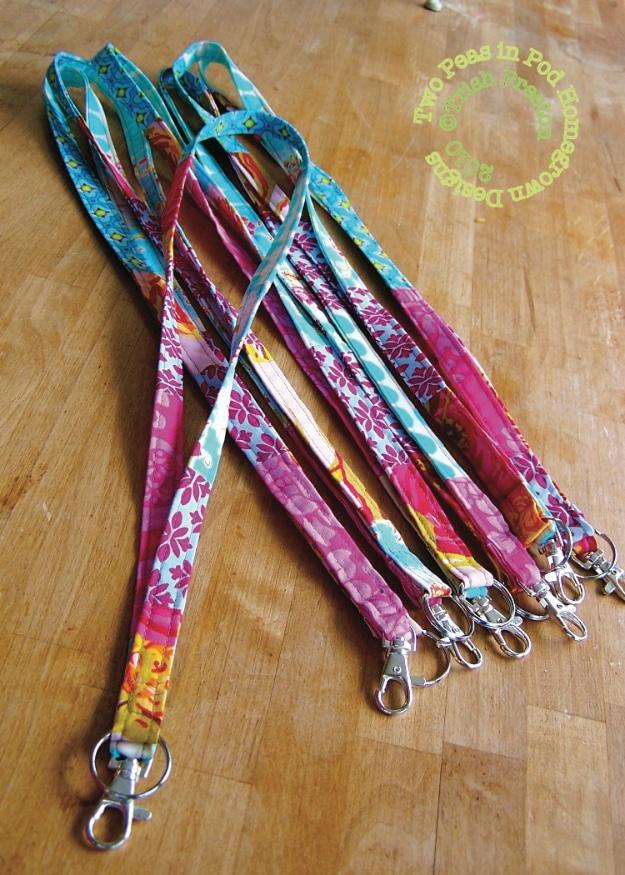 A lanyard pieced from narrow strips of cotton fabric scraps, a silver swivel clip at the bottom, hanging from a hook