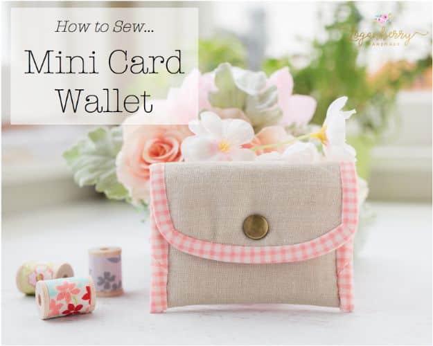 Mini card wallet, a linen card wallet with pink gingham binding and a brass snap sitting among silk flowers
