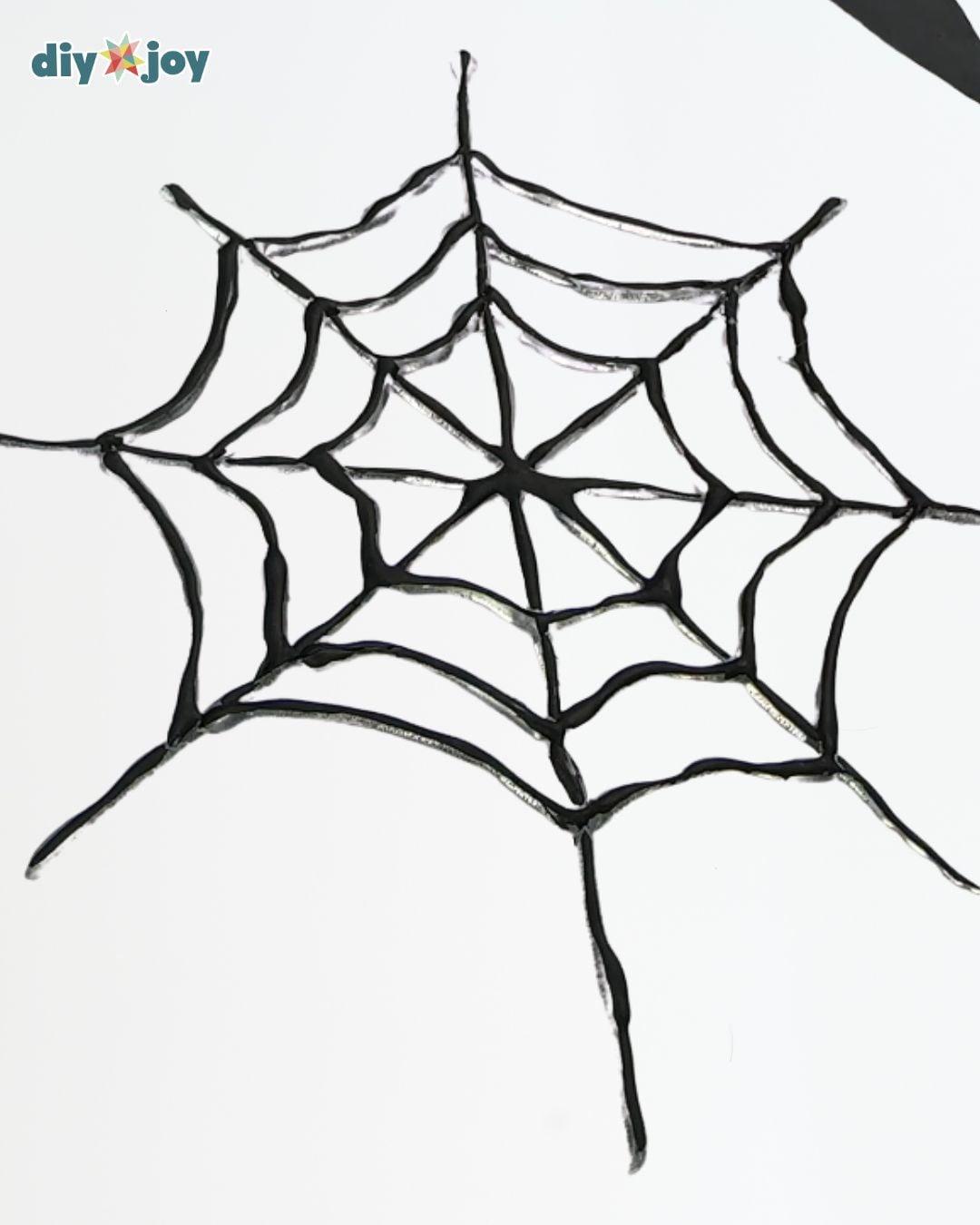 Black hot-glue spider web with irregular strands on a white background and a Sueeye logo in the upper corner