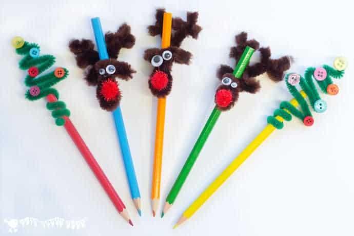 Five colored pencils topped with pipe cleaner reindeer and Christmas trees decorated with buttons and red pom pom noses