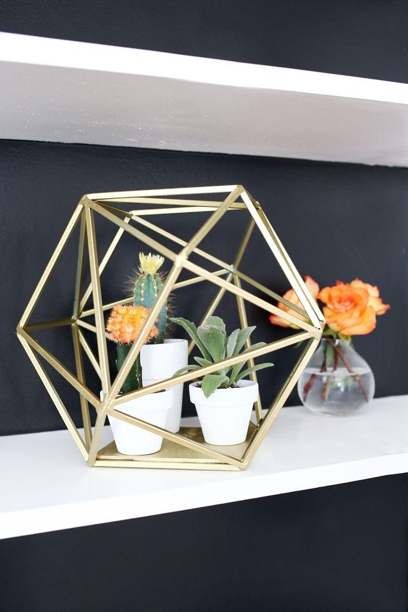 Gold geometric globe planter, a gold faceted open frame holding small white pots of cactus and succulents