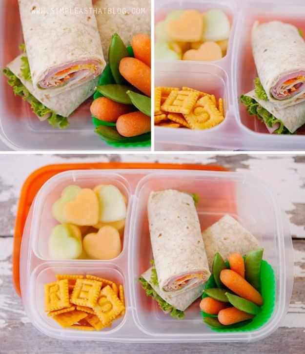 Meat, cheese and veggie wraps packed in bento boxes with baby carrots, snap peas, crackers and melon hearts