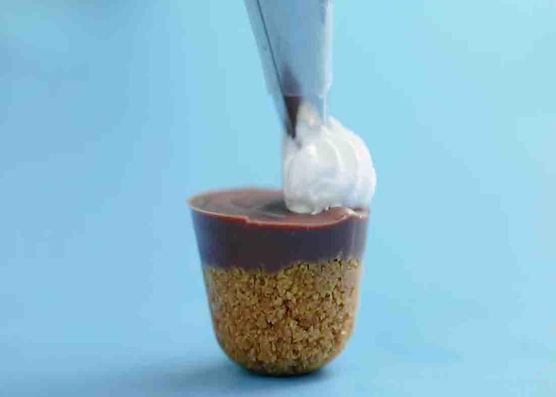 Piping some frosting on top of each bite-size-s'mores.