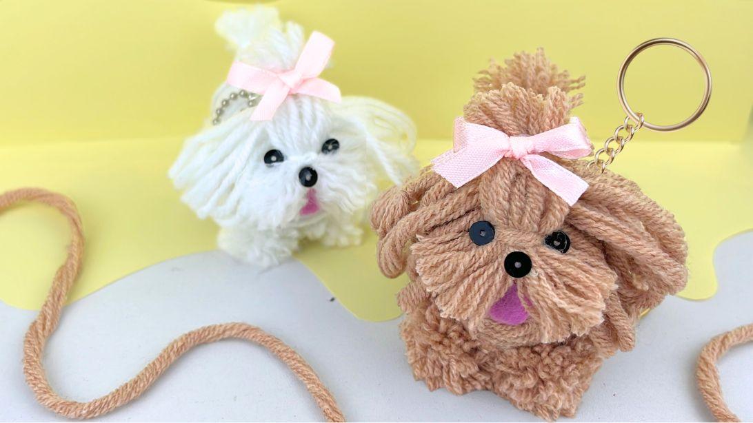 A small yarn dog with bead eyes clipped to the strap of a real handbag, a bag charm to sell on Etsy all year