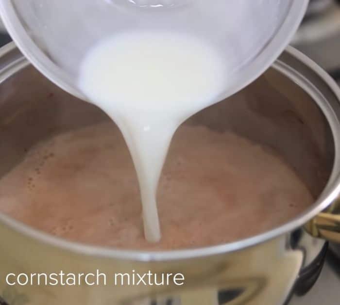 pouring cornstarch mixture into a chocolate on a pot