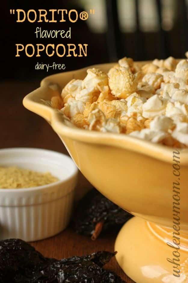 Homemade Dorito flavored popcorn heaped in a yellow footed bowl beside a white ramekin of nacho cheese seasoning
