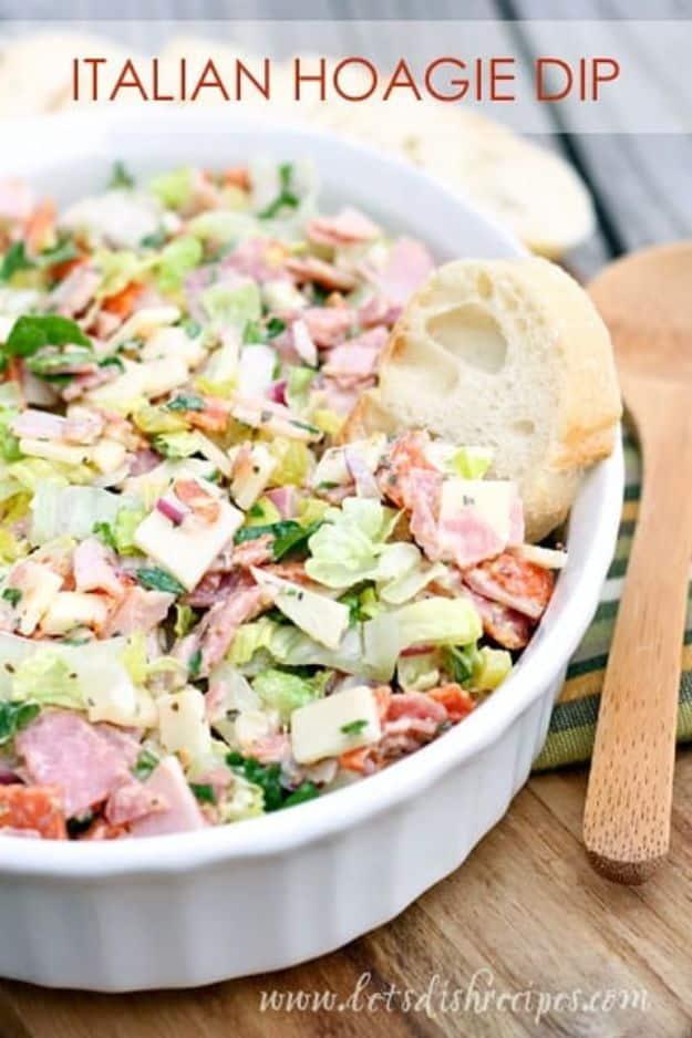 Italian hoagie dip with chopped salami, ham, provolone and lettuce in a white dish with sliced baguette
