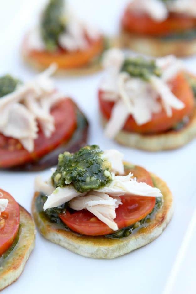 Chicken pesto bites built on roasted sweet potato rounds with tomato and shredded chicken, gluten free