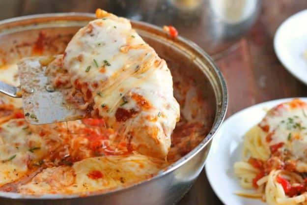 Italian style chicken mozzarella skillet with cutlets in tomato pesto sauce under browned melted cheese