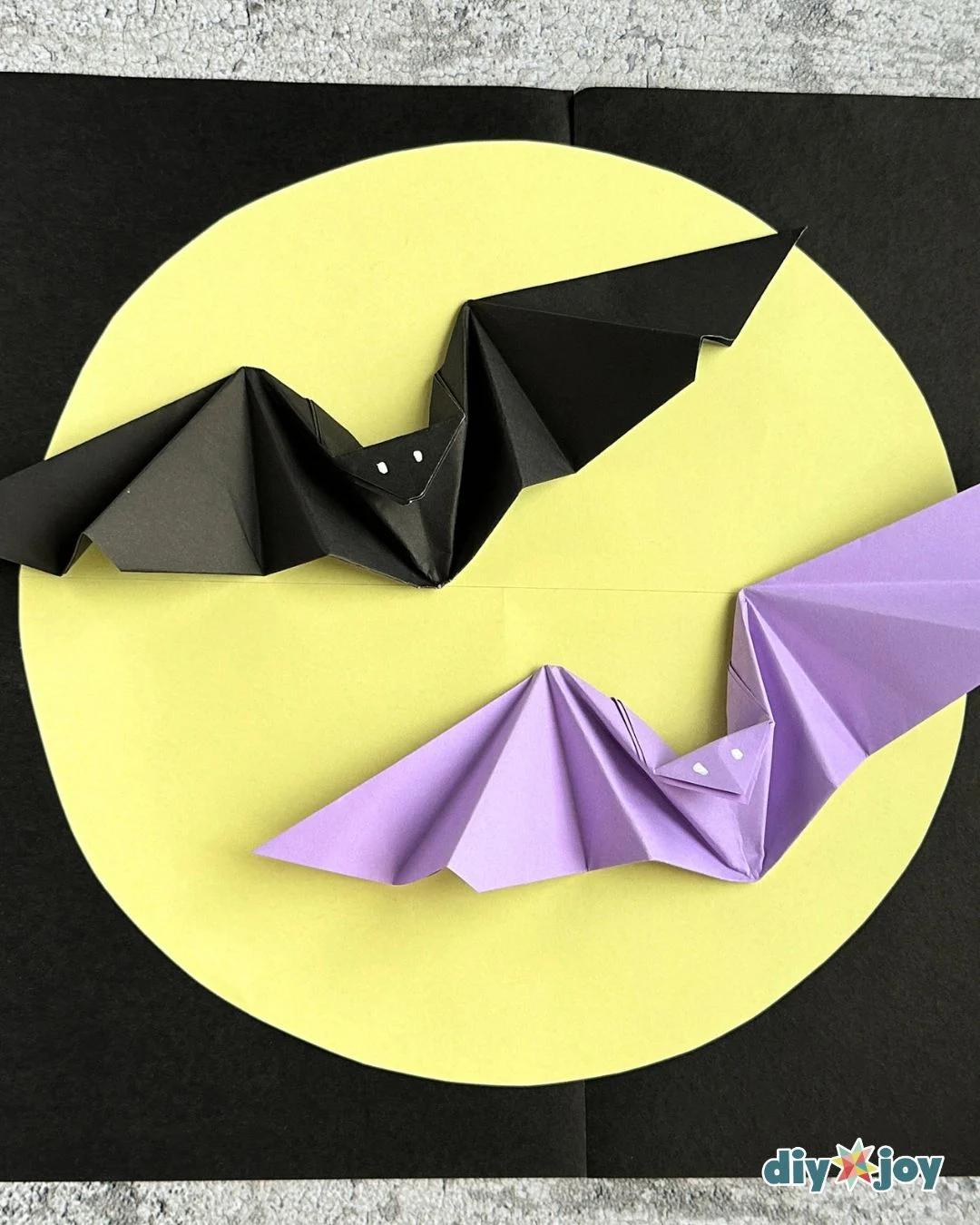 Halloween origami bat held in hand to show the flapping wings, folded from one square of colored paper.