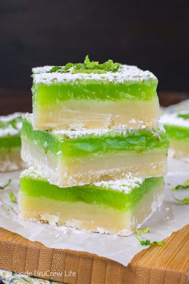 Stacked key lime bars with a bright green lime filling on shortbread crust dusted with powdered sugar