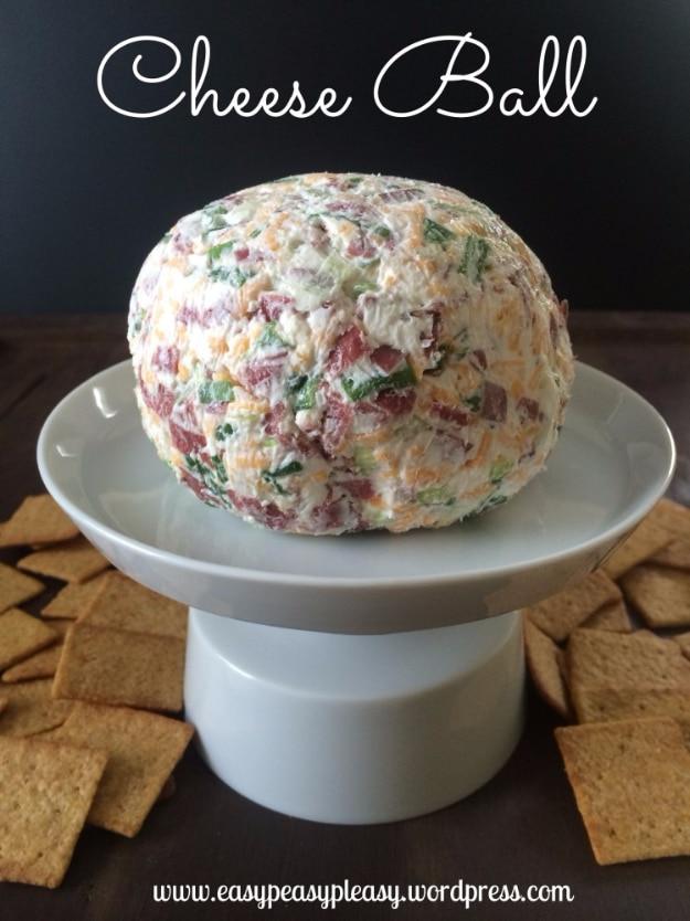 Super delicious cheese ball rolled in chopped nuts and herbs on a board surrounded by crackers and knives