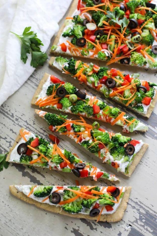 Gluten free veggie pizza cut into long rectangular slices topped with broccoli, carrots, peppers and olives