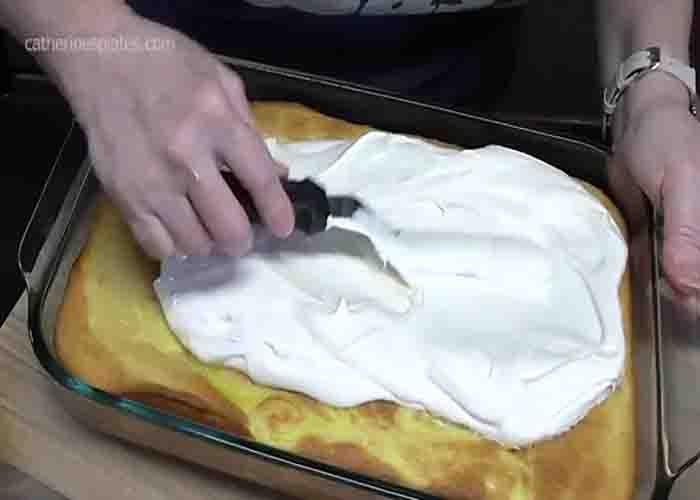 Adding the frosting on top of the lemon cake