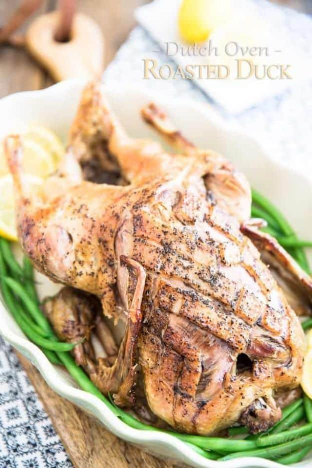 Whole duck roasted in a dutch oven with scored criss cross skin, cooked slowly until golden and tender
