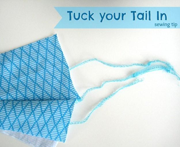 Serger sewing tip tuck your tail in, a folded blue patterned fabric with long pale serger thread tails trailing from the seam