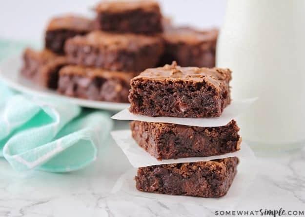 Best homemade brownies stacked on parchment beside a glass of milk with a soft fudgy chocolate crumb