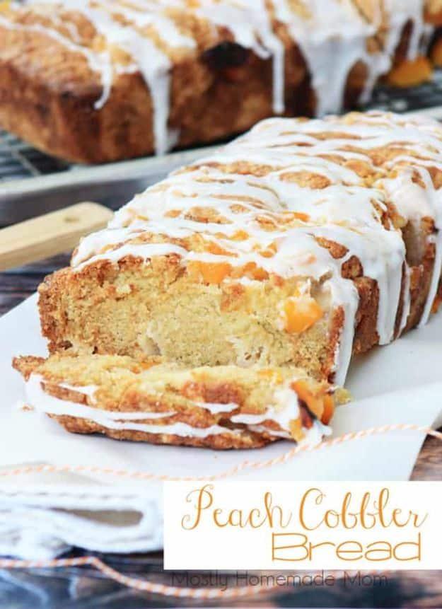 Peach cobbler bread sliced with white glaze drizzled over the top and peach pieces visible in the crumb