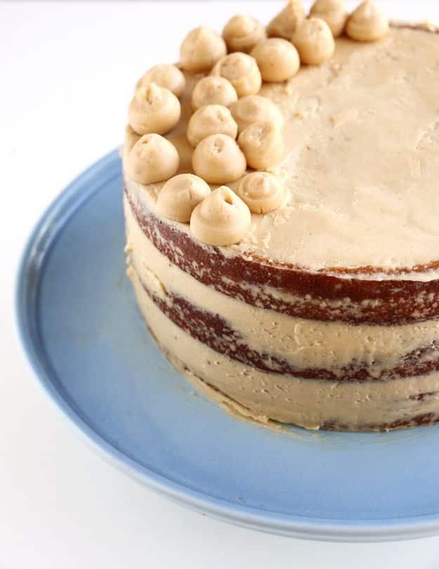 Three layer coffee cake with pale coffee buttercream between the layers and piped dots on top, on a blue plate