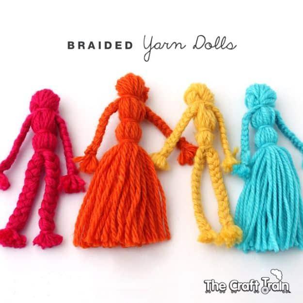 Four braided yarn dolls in pink, orange, yellow and teal lying in a row, two with braided legs and two with skirts