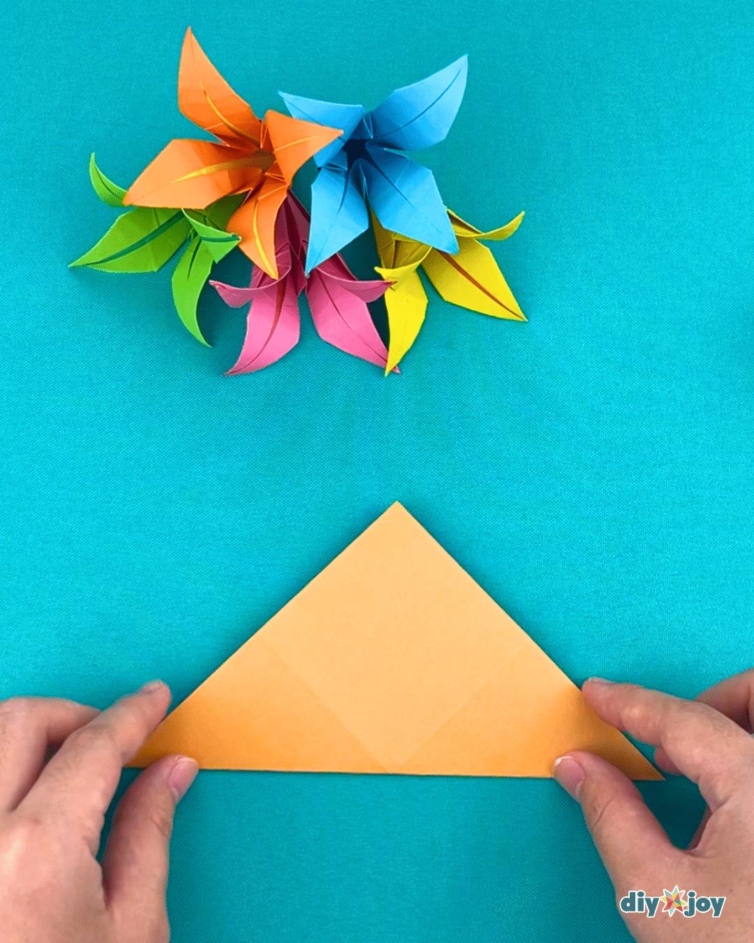 Origami lily flower folded from a square of paper, one of the diagonal folding steps in the paper flower tutorial