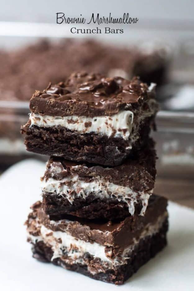 Brownie marshmallow crunch bars stacked showing a white marshmallow layer under a crunchy chocolate top