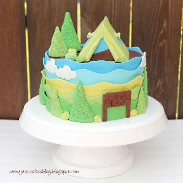 Round baby shower cake with a blue and green fondant landscape, fondant trees and a small tent on top