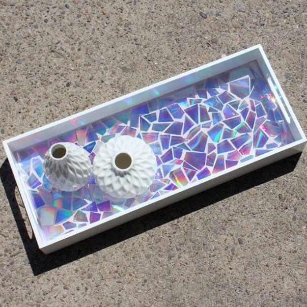 White serving tray filled with a mosaic of iridescent CD pieces under clear glossy resin, with two vases