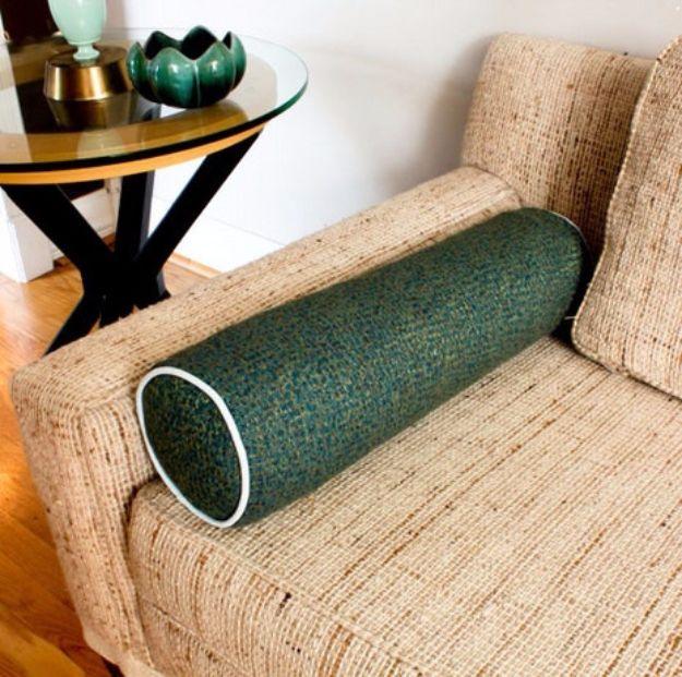 Beefy bolster pillow made from rolled old towels in a green tweed cover, lying across the seat of a woven couch
