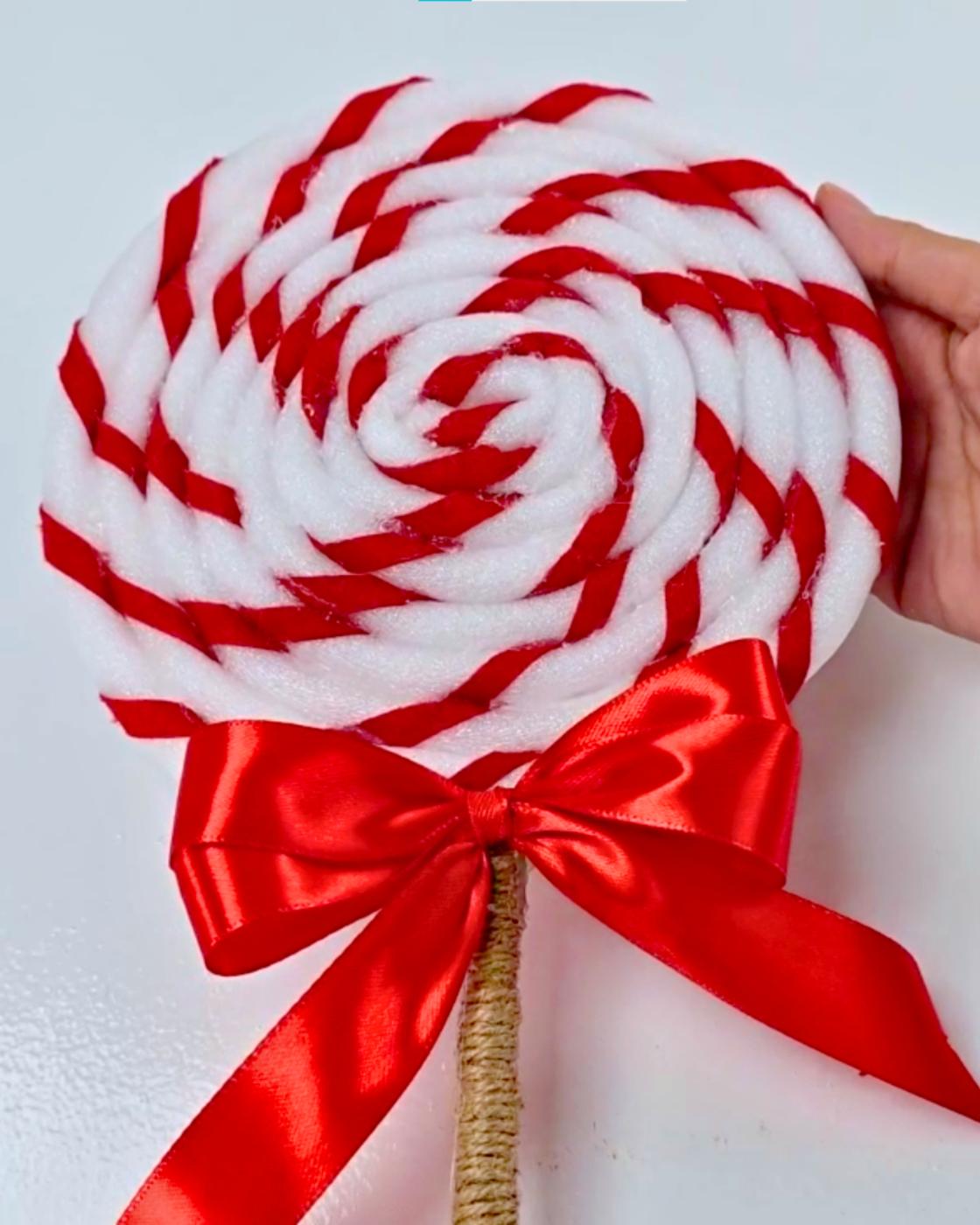 Candy Costume - the finished giant red and white swirl lollipop prop mounted on a twine wrapped stick with a satin ribbon bow