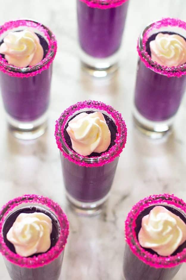 Candy sweet jello shots in sprinkle rimmed glasses with triple sec whipped cream piped on top of each