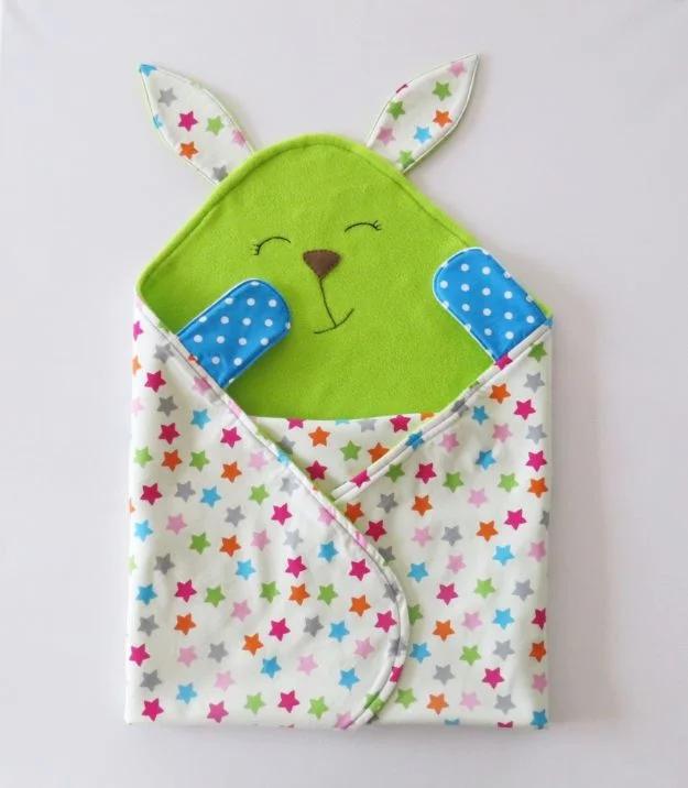A flannel baby blanket with a soft stuffed toy stitched to one corner, its face embroidered rather than beaded.