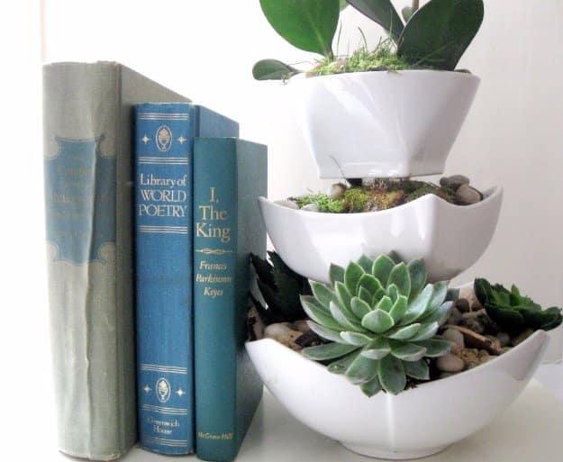 A wide thrifted ceramic bowl planted with green and dusty pink succulent cuttings over a layer of pale drainage gravel