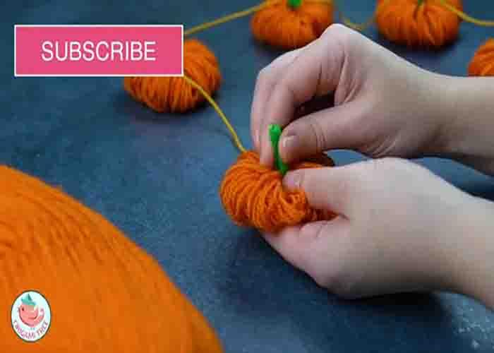 Putting a stem to the yarn pumpkin using a pipe cleaner