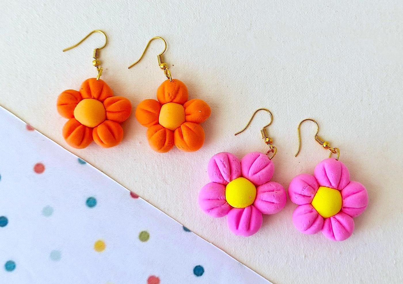 Clay flower dangle earrings, two orange and two pink five petal flowers with yellow centers on gold hooks by dots
