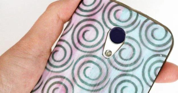 A decoupaged clear phone case with a hand cut swirl paper pattern sealed on top, a cheap handmade accessory craft to sell