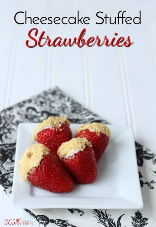 Cheesecake stuffed strawberries piped with creamy filling and topped with graham cracker crumbs on a plate