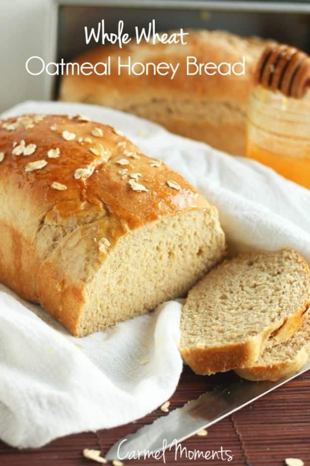 Whole wheat oatmeal honey bread sliced to show a soft crumb, with rolled oats scattered on the crust