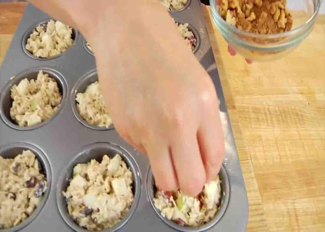 Distributing the apple oatmeal mixture into the muffin cups