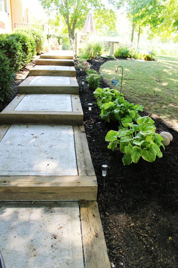 Concrete sidewalk stepping down a sloped yard in sections retained by heavy pressure treated timber beams