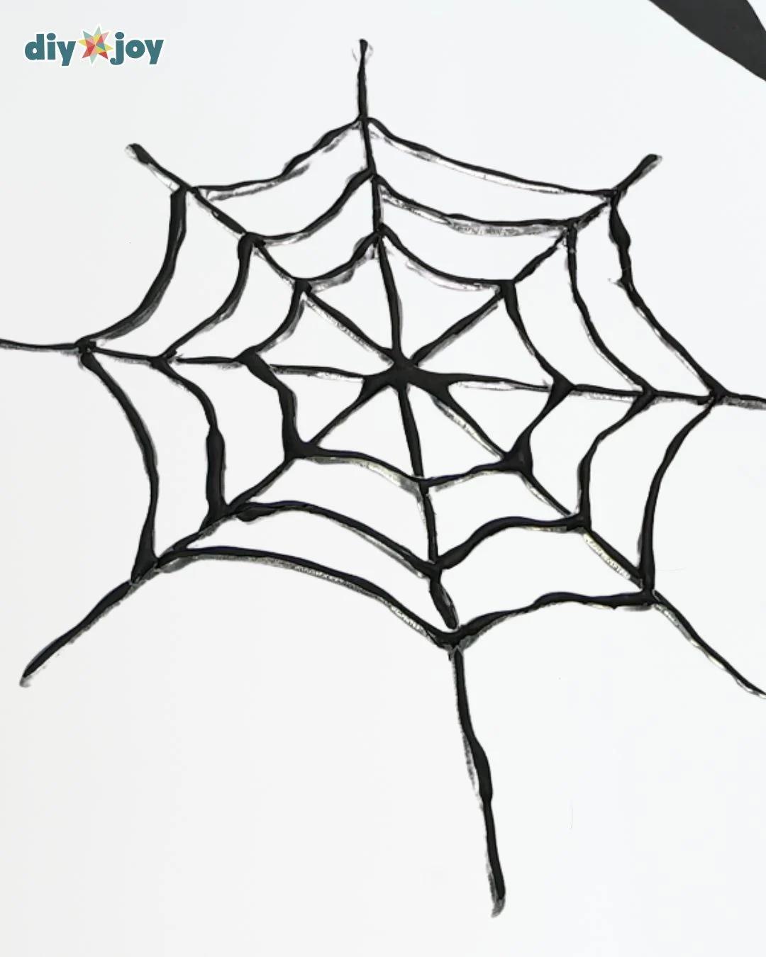 Cheap Halloween Decor - one finished black spider web made from hot glue, photographed alone on a plain white surface