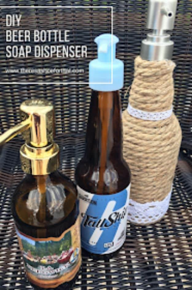 Three beer bottle soap dispensers on wicker, one plain with its label, one wrapped in jute rope, one with rope and lace