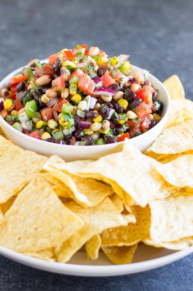 Cowboy caviar in a bowl with black beans, black eyed peas, corn, tomatoes, peppers and cilantro at a backyard cookout