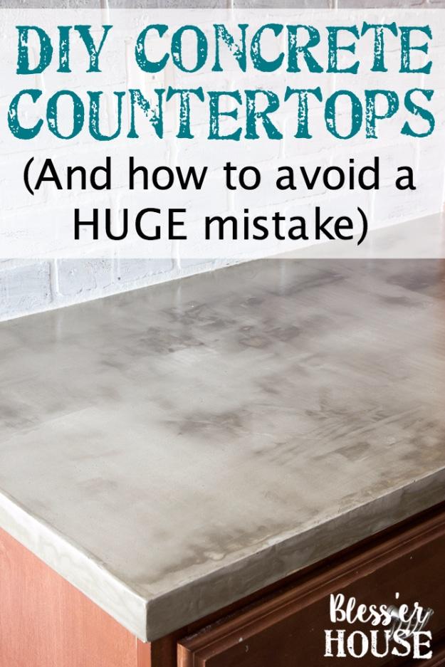 Grey feather finish concrete countertop with mottled surface on a wood cabinet, against a whitewashed painted brick wall